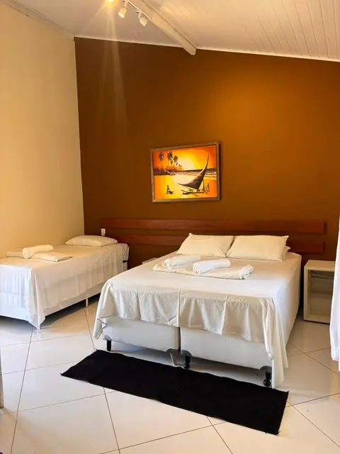 Cama de casal e cama de solteiro no mesmo quarto, com frigobar.